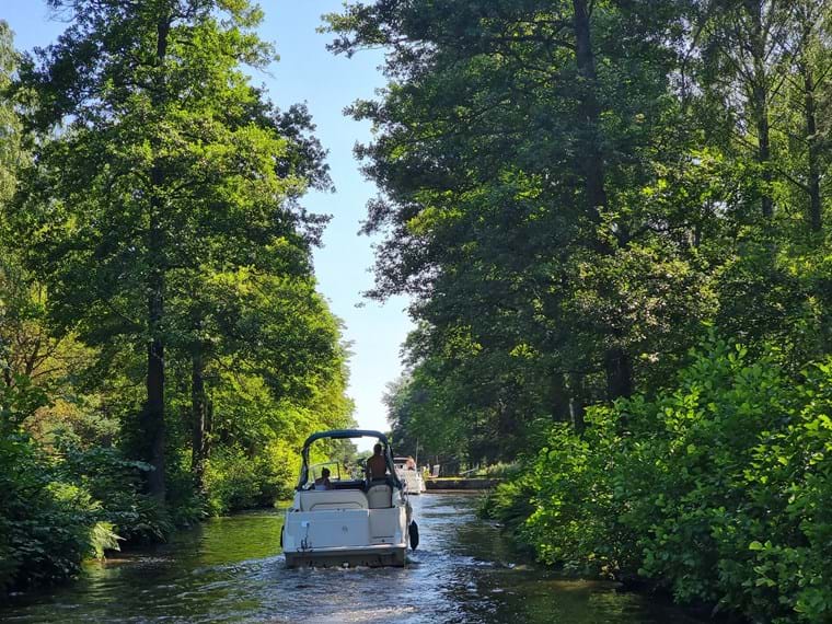 Båtar i kanalen, omringad av gröna träd